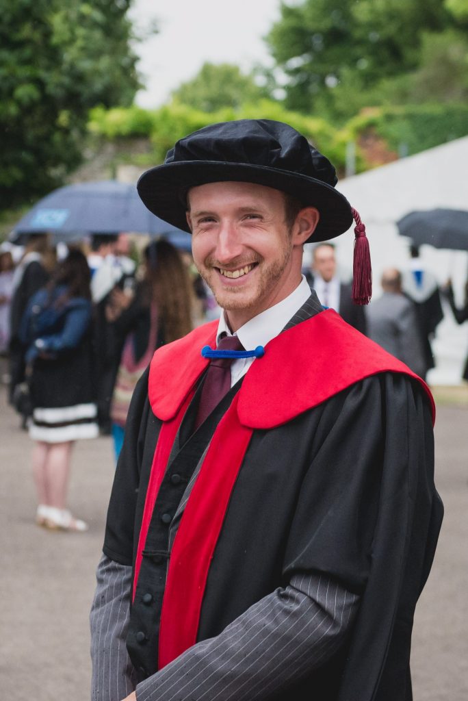 Chris Henry smiling in PhD robes
